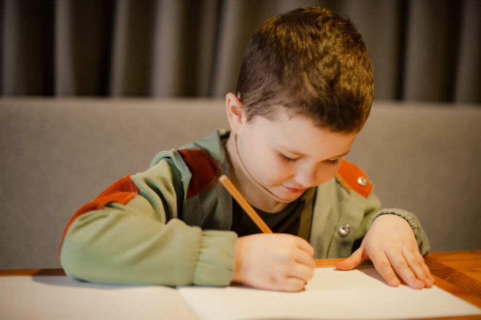 Child expressing creativity with pencils in cafe